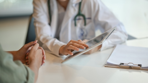 A doctor speaks with a patient in an exam room