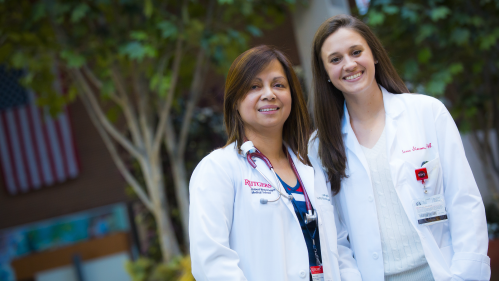 Advanced practice nurse Lalaine Genuino and certified physician assistant Alexa Simon talking in atrium
