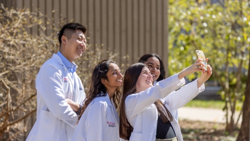 Students in white coats take a selfie