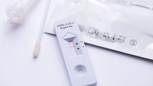A COVID test strip and swab sit on a table