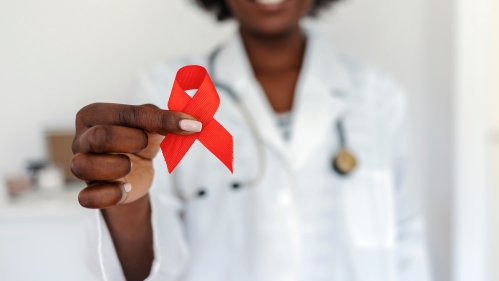 A doctor holds up a red ribbon for HIV/AIDS prevention and awareness