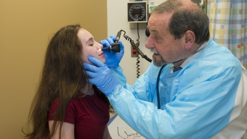A doctor looks into a young patient's nose during an exam
