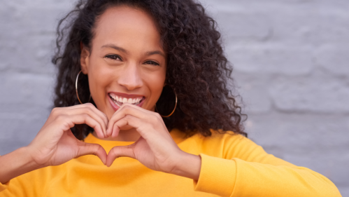 Image of woman making a heart with her hands for Kindness