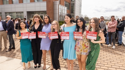 Women Med Students holding up signs that say where they matched 