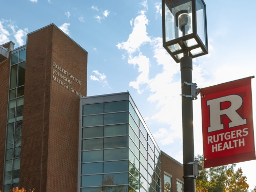 A Rutgers Health banner hangs on a light pole on campus in front of RWJMS
