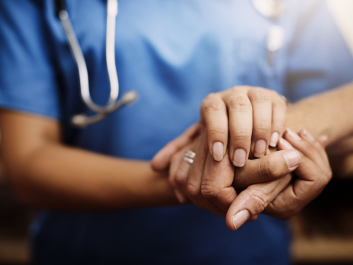 A medical professional holding hands with a patient