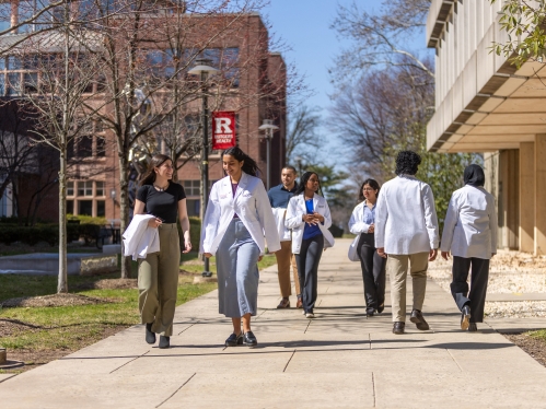 Medical school students walk on a sidewalk on Busch Campus