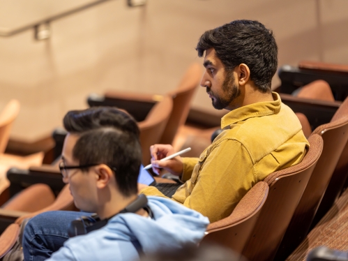 Two students listen to the professor in a lecture hall