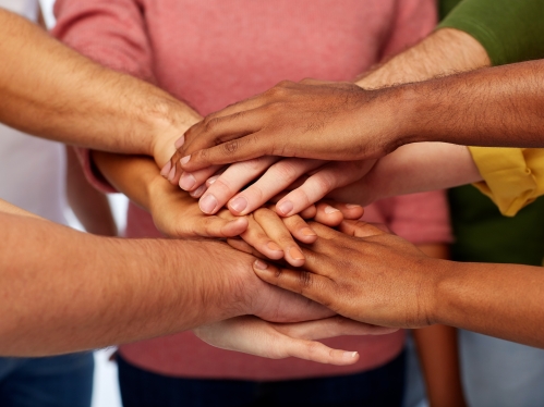 Diverse hands stacked in a circle to symbolize teamwork and community