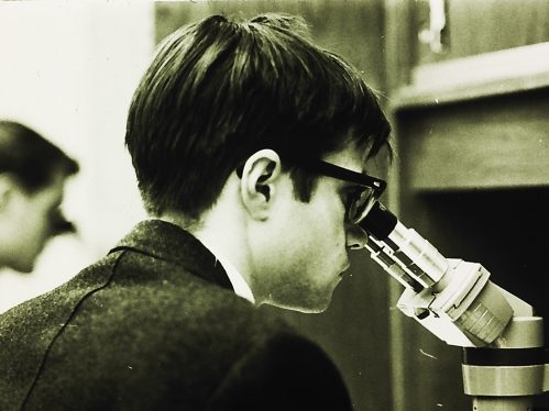 Black and white historic photo of a student looking into a microscope