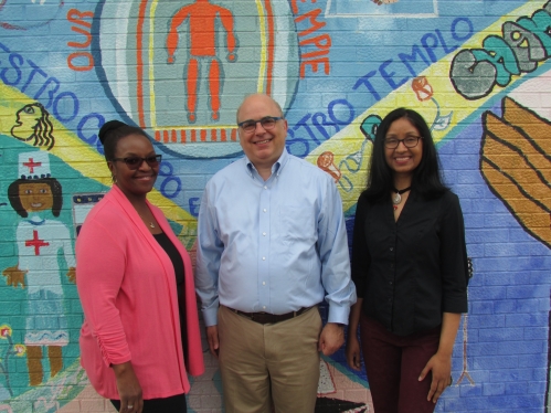 Three pediatrics faculty members stand in front of the mural outside the Eric B. Chandler Health Center