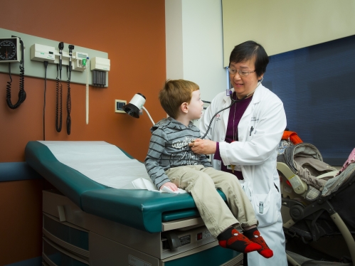 A pediatrician listens to a young patient's heart