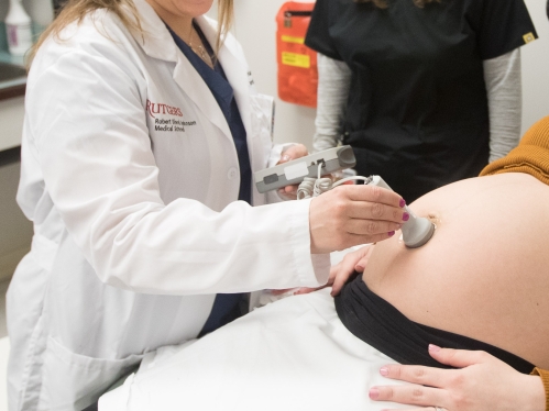 A doctor uses a doppler on a pregnant patient to listen to a fetal heartbeat 