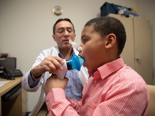 A doctor measures a young patient's breathing in an exam room