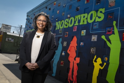 Dr. Shawna Hudson stands in front of a mural in New Brunswick