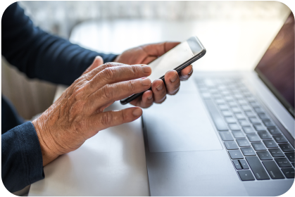 Image of man using cellphone in front of a computer