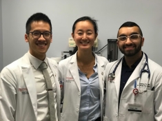 Three Promise Clinic student doctors stand in an exam room