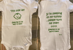 Image of a baby onesie with directions on how to place a baby down for sleep