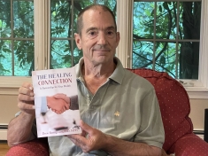 Doctor holding a copy of his book.
