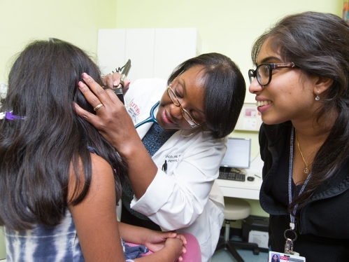A doctor looks into a young patient's ears